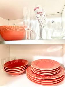 a pile of red plates and wine glasses on a shelf at Appartement in Fort-de-France