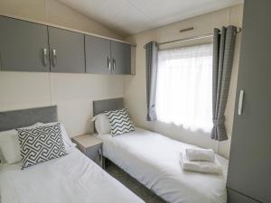 Duas camas num pequeno quarto com uma janela em Long Acres Lodge em Evesham