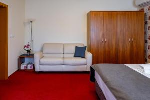 Relax Hotel Stork في ليدنيس: غرفة نوم مع أريكة بيضاء وكرسي