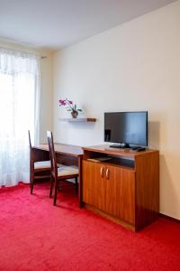 a living room with a television and a dining table at Relax Hotel Stork in Lednice