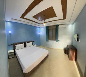 a bedroom with a white bed and blue walls at IGHIZ INN resort in Er Rachidia