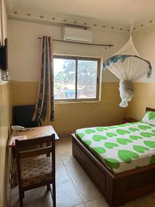 - une chambre avec un lit, une table et une fenêtre dans l'établissement Gust Hotel, à Bangui