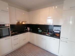 una cocina con armarios blancos y encimeras negras en Appartamento Roby, en Solduno