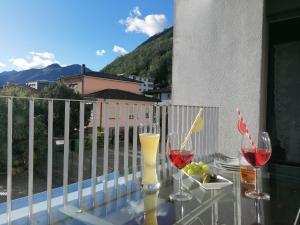 dos copas de vino sentadas en una mesa de cristal en un balcón en Appartamento Roby, en Solduno