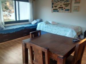Zimmer mit einem Tisch, einem Bett und einer Bank in der Unterkunft Monoambiente céntrico equipado - AlquilaMiCasa in San Martín de los Andes