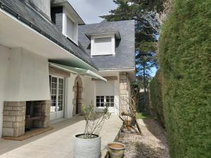une maison blanche avec une terrasse couverte ornée de plantes en pots dans l'établissement Villa Topaze La Baule les Pins, à La Baule