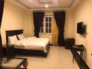um quarto com uma cama e uma televisão em Magnum Hotel em Battakundi