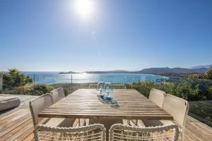 un tavolo di legno con sedie e vista sull'oceano di Villa a Luna Ruscana a Sainte-Lucie de Porto-Vecchio Altre 14 foto