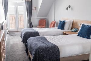 Habitación de hotel con 3 camas con almohadas azules en The Elizabeth, en Sidmouth