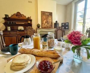 una mesa cubierta con una mesa con pan y zumo de naranja en La Maison Voyage Bed and Breakfast, en Onzain
