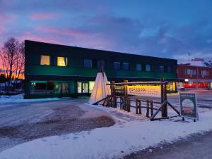 un edificio con un cartel delante de él en la nieve en Pine Sky Apartments, en Ivalo