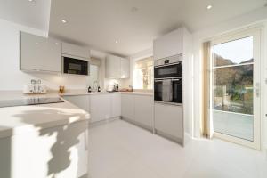 een witte keuken met witte kasten en een raam bij Tors Park in Lynmouth