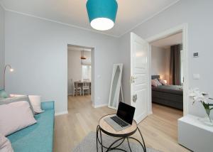 una sala de estar blanca con un ordenador portátil sobre una mesa en Kalamehe Apartment 4 near City center, en Pärnu