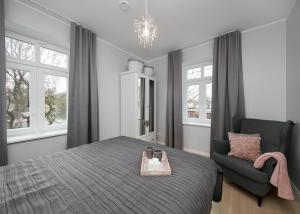 a bedroom with a bed and a chair and windows at Kalamehe Apartment 4 near City center in Pärnu