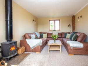a living room with a couch and a stove at Siskin Barn in Bidford