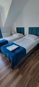 two beds in a bedroom with a blue headboard at Apartamenty Koło Brzegu in Gąski