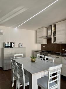 a kitchen with a wooden table and white chairs at Holiday House in Palermo