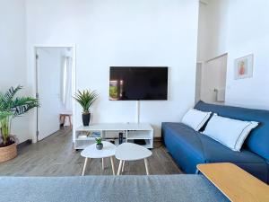 ein Wohnzimmer mit einem blauen Sofa und einem TV in der Unterkunft Villa Romane private pool breathtaking sea view in Anse Marcel 