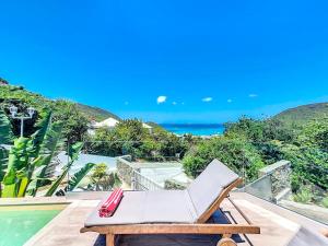 ein weißer Sessel auf einem Balkon neben dem Pool in der Unterkunft Villa Romane private pool breathtaking sea view in Anse Marcel 