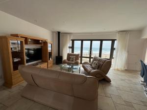a living room with a couch and chairs and a television at Beachfront Heaven in Hentiesbaai