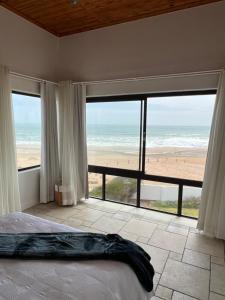 a bedroom with a bed and a view of the beach at Beachfront Heaven in Hentiesbaai