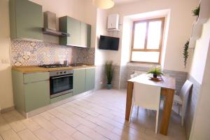 a kitchen with green cabinets and a table and a window at Holidayhouse Ostia - Libeccio in Lido di Ostia