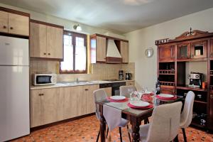 a kitchen with a table and chairs and a white refrigerator at Villa Sevi Grande by PosarelliVillas in Káto Vení