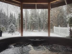 a bath tub in a room with a snow covered yard at La Casa del Plage - Spa privé et Hamak in Sainte-Lucie-de-Doncaster
