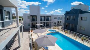 ein Apartment mit einem Pool und 2 Sonnenschirmen in der Unterkunft Apart del Golfo in Las Grutas