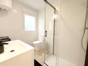 uma casa de banho branca com um chuveiro e um WC. em Apartamento reformado en Santoña em Santoña