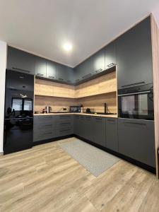 a kitchen with black cabinets and a wooden floor at Apartman Sandra in Nova Gradiška