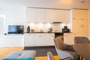 バーゼルにあるSpecial EiNSTEiN I Apartment Basel, Messe Kleinbasel 10-STARの白いキャビネット、テーブルと椅子付きのキッチンが備わります。