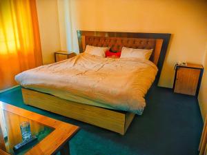 Schlafzimmer mit einem großen Bett mit einem Kopfteil aus Holz in der Unterkunft Lashari Resort in Skardu