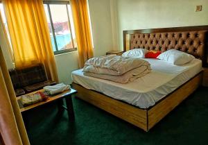 Schlafzimmer mit einem Bett mit einem Holzrahmen und einem Fenster in der Unterkunft Lashari Resort in Skardu