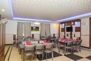 a dining room with tables and chairs and a tv at Aerocity Hotel Zindal Plaza at Delhi Airport in New Delhi