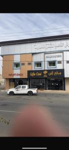 een witte auto geparkeerd voor een gebouw bij أرض الذهب للشقق المخدومة in Khunayfsah