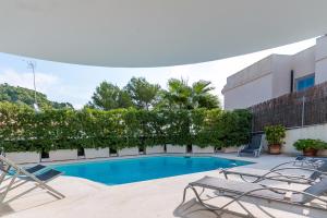 a swimming pool with two lounge chairs next to a building at Casa Noa in Alcudia