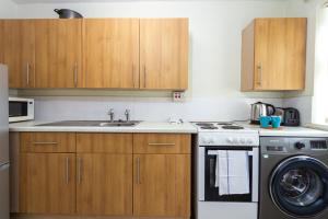 een keuken met houten kasten, een wastafel en een vaatwasser bij Convenient 1Bed Apt Close to Transport Links in Manchester