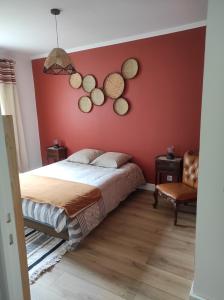 um quarto com uma parede vermelha com uma cama e uma cadeira em Apt calme, proche hôpital, centre ville em Brive-la-Gaillarde