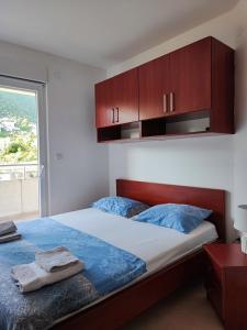 Schlafzimmer mit einem Bett mit Holzschränken und einem Fenster in der Unterkunft PORTONOVIPRC in Herceg-Novi