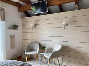 a bedroom with two chairs and a tv on a wall at Escale sur la Côte in Porrentruy