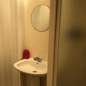 La salle de bains est pourvue d'un lavabo et d'un miroir. dans l'établissement Camping Atypique Manche SURVILLE, à Surville