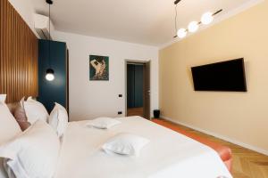 um quarto com uma cama branca e uma televisão na parede em Hypnose Resort em Vadu