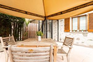 une table et des chaises en bois sous un grand parasol dans l'établissement Gelsomino Stone House, à Stazzona