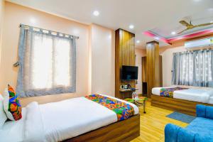 a bedroom with two beds and a couch and a tv at HOTEL KANAN INN in kolkata