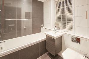 een badkamer met een wastafel, een bad en een spiegel bij Cobble Cottage in Whitby