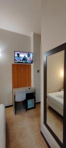 Hotel Nuovo Rondò في سيستو سان جيوفاني: غرفة نوم مع سرير وتلفزيون على الحائط