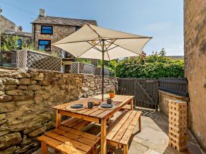 a wooden table with an umbrella on a patio at 4 Bed in North Pennines 92351 in Alston
