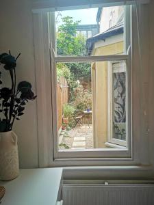 a window with a vase of flowers on a counter at 1-Bed victorian gf Apartment in London in London