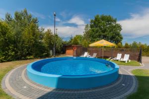 uma piscina num quintal com cadeiras e um guarda-sol em Flatbook - Sztutowo Lazurowy Dwór em Sztutowo